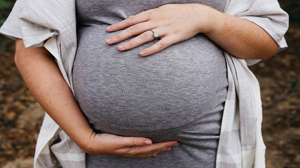 Schwangere Frau hält ihren Bauch.